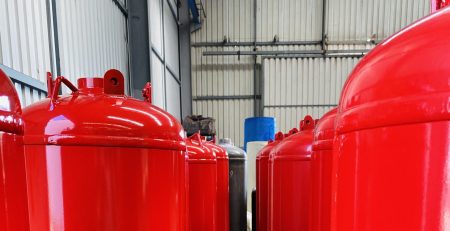 Production line of red TPED-certified clean agent fire suppression cylinders ready for shipment