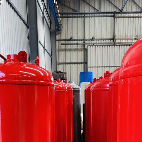Production line of red TPED-certified clean agent fire suppression cylinders ready for shipment